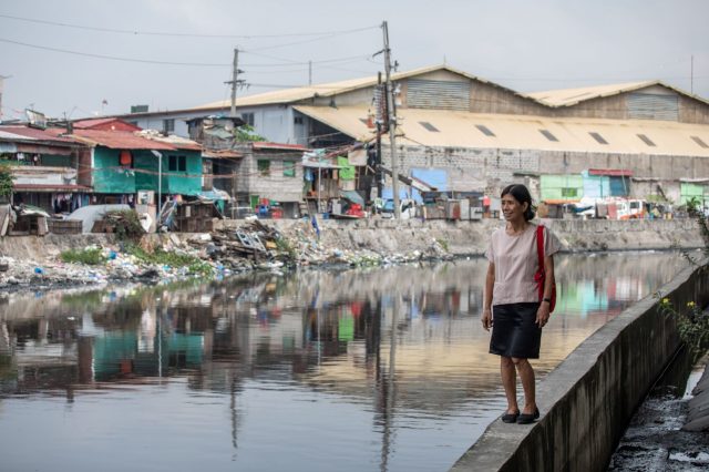 Mam'Percy près d'une étendue d'eau dans le bidonville de Saatas, à Manille aux Philippines